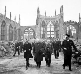 Winston Churchill walking through the ruined nave of Coventry Cathedral, after it was severely damaged in the Coventry Blitz of 14–15th November 1940 | Image taken by Capt Horton, War Office official photographer, Courtesy of Imperial War Museum. H_14250 Imperial War Museum Archives