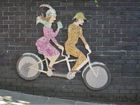 Mural mosaic of tandem bicycle with man steering and woman drinking from a can, Coventry, 2020 | Image courtesy of Anne Langley