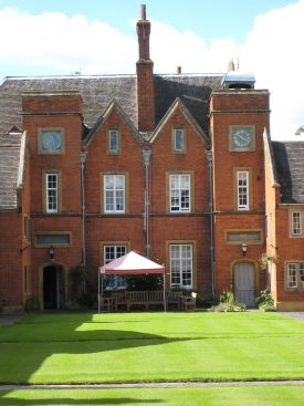 Master's House at Lady Katherine Leveson's Hospital, 2007. Red brick 3-storey building with stone dressings and slate roof,; clock on tower. Lawn in front and awning over wooden seats. | Image courtesy of Anne Langley