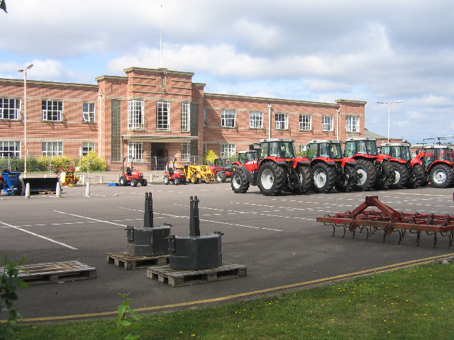 A red brick office block with frontage, red tractors and a car park | Photo © David Stowell (cc-by-sa/2.0). Originally uploaded to geograph