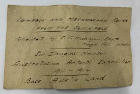 The label reads: ‘Igneous and metamorphic rocks from the South Pole. Collected by C.T. Madigan Esquire, Magdalen College, Oxford. Sir Douglas Mawson Australasian Antarctic Expedition, 1911-1914. Base Adelie Land’. | Image courtesy of Warwickshire Museum