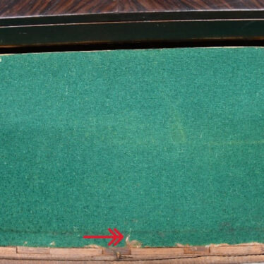 The base of the drawer, covered with felt, showing signs of moth. The red arrows indicate where the damage is Green baize on a wooden backing. Two red arrows are imposed over the image at the base, centre and right, showing where the moths have damaged the item. | Image courtesy of Victoria Young