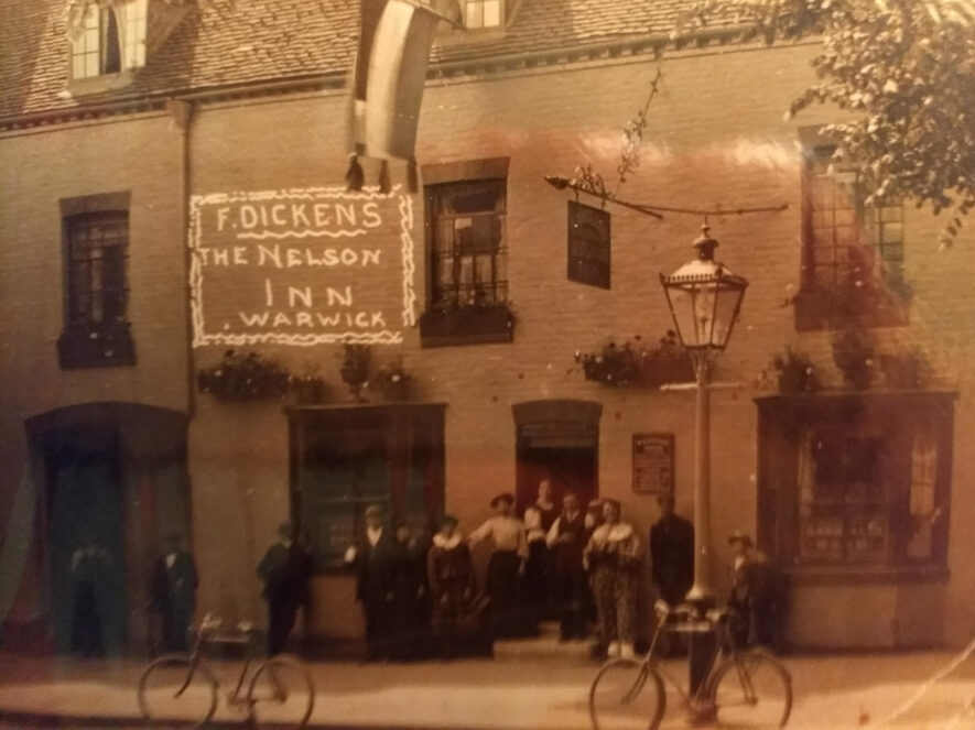 Warwick. The Nelson Inn. 1910-1916. A sepia coloured photograph of a rendered pub, with cyclists and drinkers outside of it. | Image courtesy of Kathleen Cason